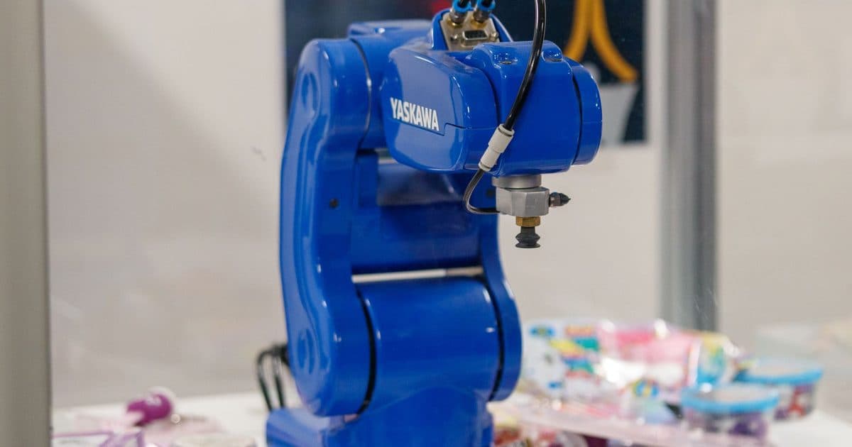 A blue industrial robot arm in a manufacturing setting.