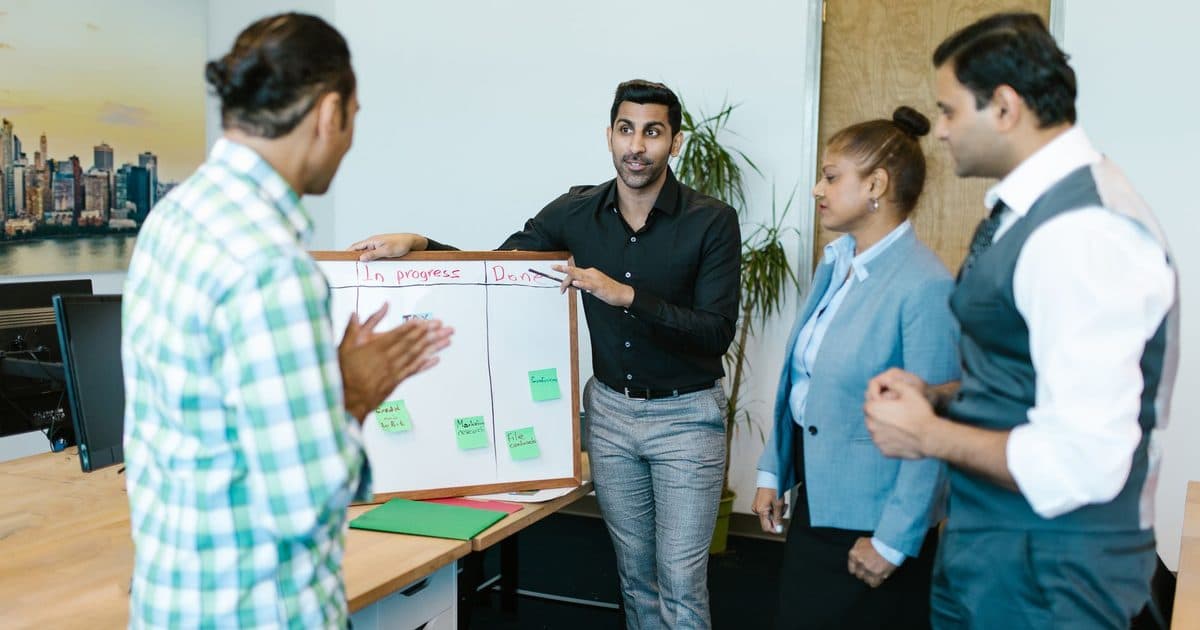 A team standing around a whiteboard to discuss progress.