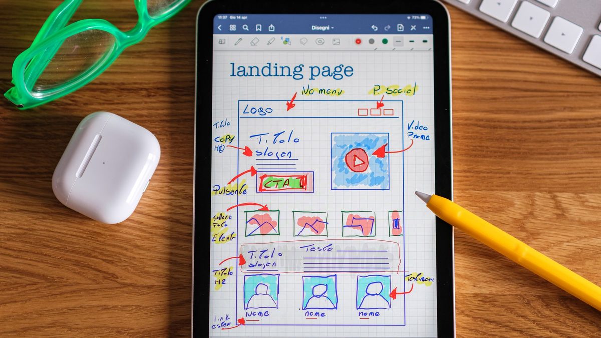 A tablet showing a hand-drawn landing page wireframe.