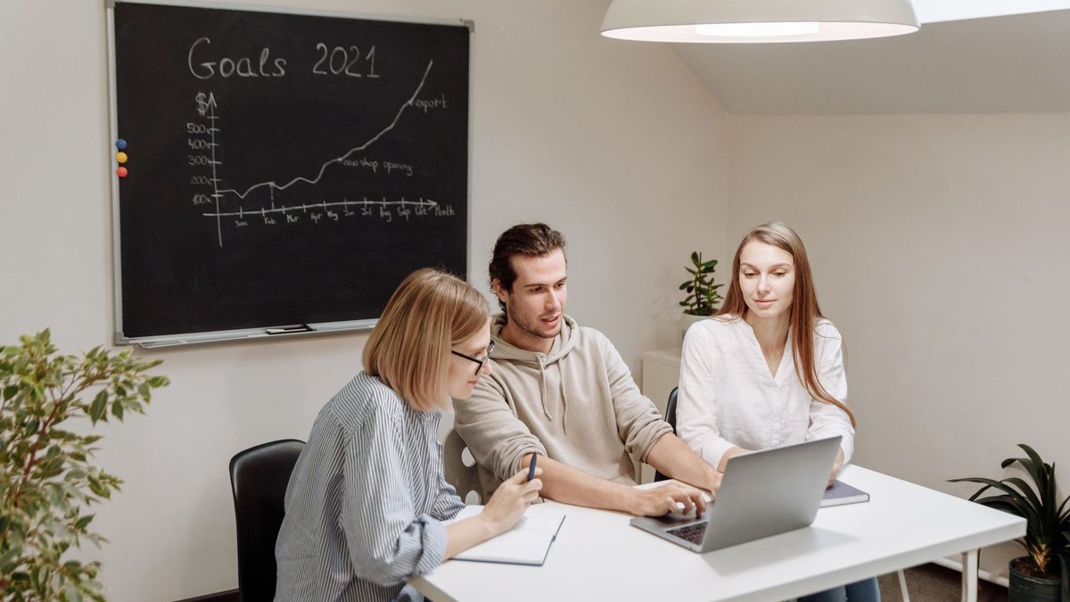 A team planning goals at a table with a laptop.