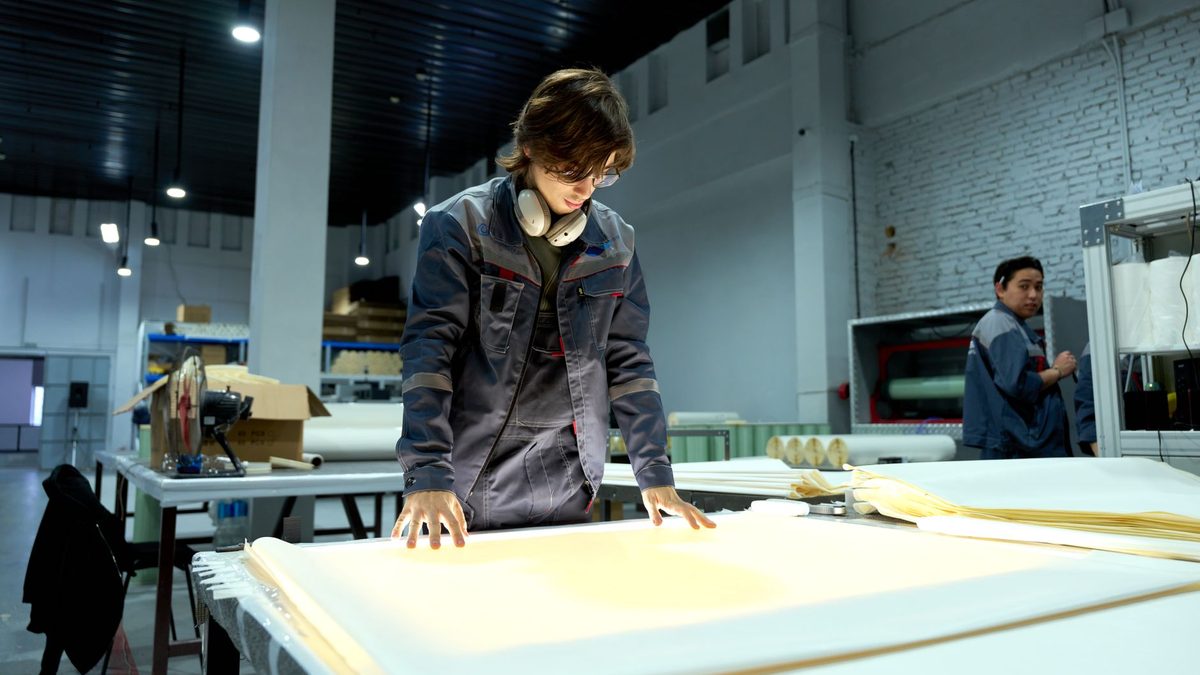A worker inspecting sheets in a factory.