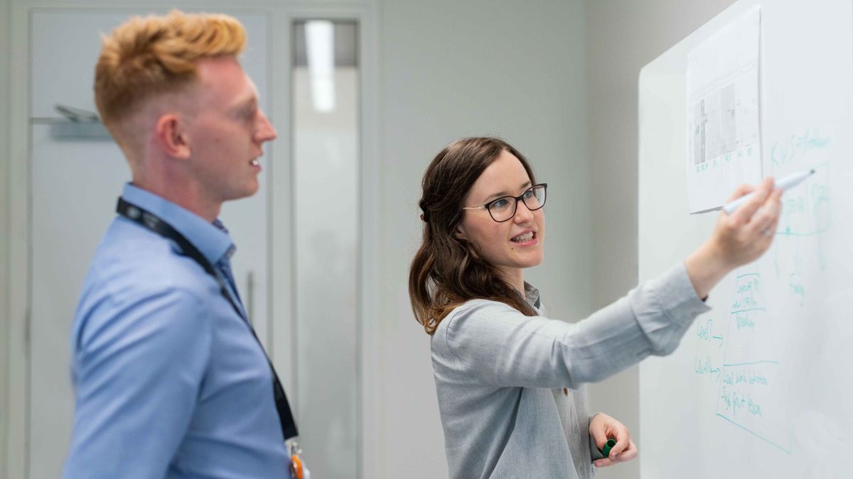 Two colleagues discussing architecture at a whiteboard.