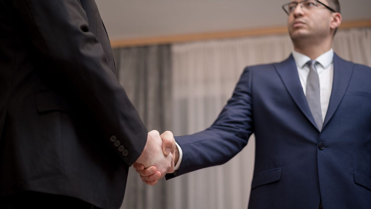 Two people shaking hands in a business meeting.