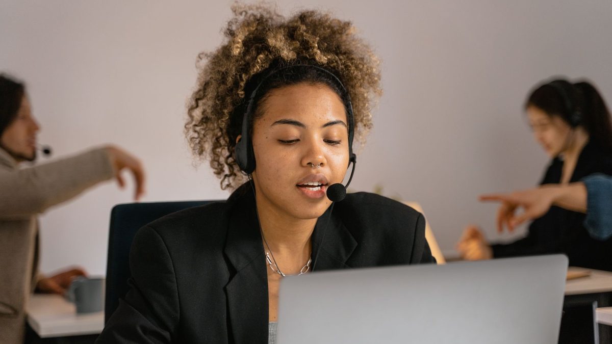 A support agent wearing a headset while working at a computer.