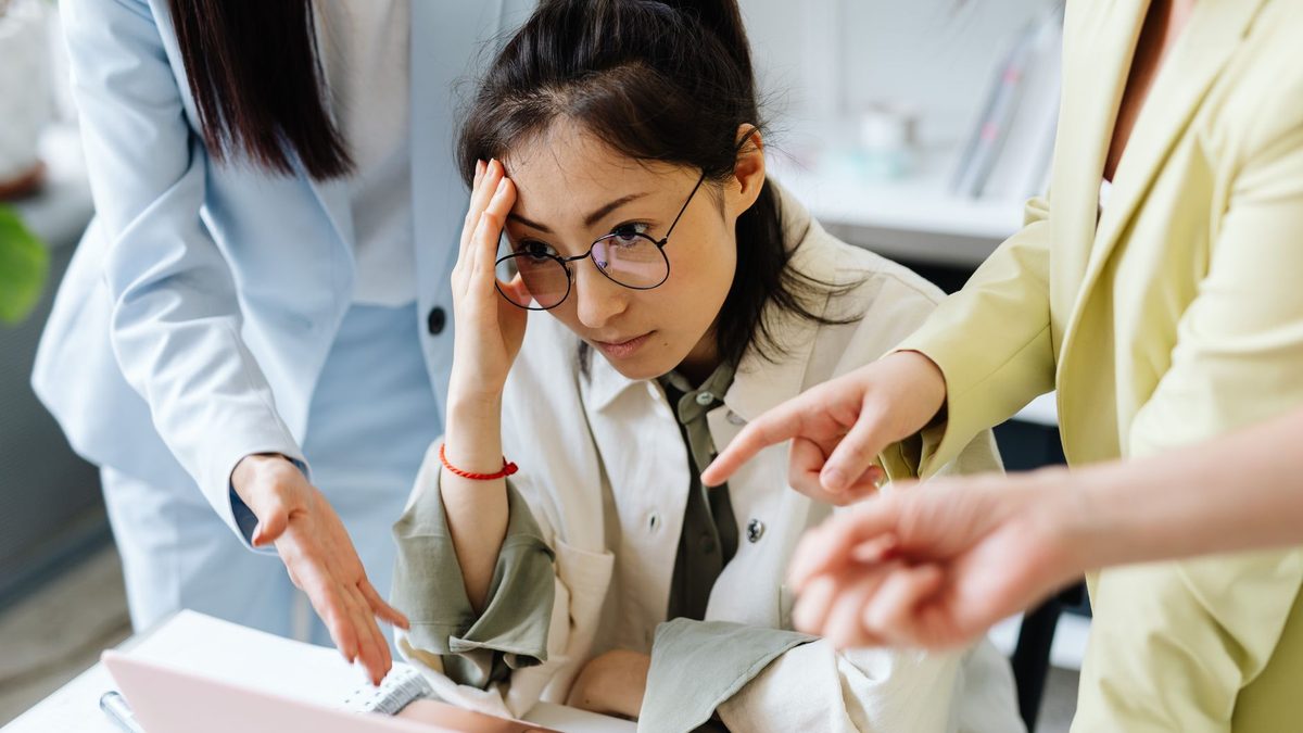 A team at a laptop looking frustrated during a discussion.